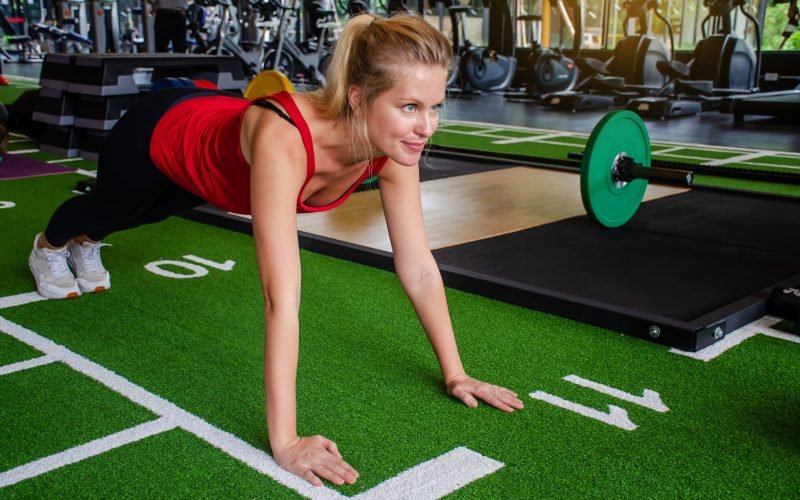 Close up young woman doing push-ups at the gym. Muscular female doing pushups on exercise at gym, Fitness exercise and healthy concept.